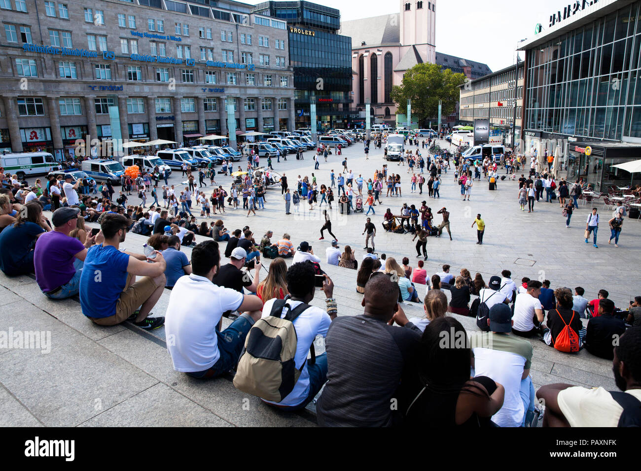 people sitting on the stairs form the cathedral square to the main station and listen street musicians, Cologne, Germany.  Menschen sitzen auf der Tre Stock Photo