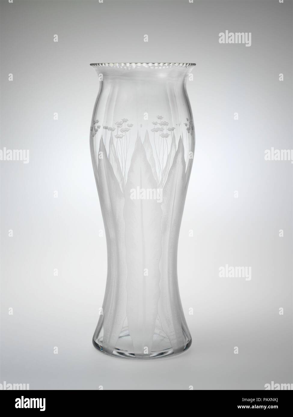 Vase. Culture: American. Dimensions: H. 14 1/4 in. (36.2 cm); Diam. 15 in. (38.1 cm). Manufacturer: C. Dorflinger and Sons (American, White Mills, Pennsylviania, 1881-1921). Date: 1905-15.  In contrast to the deeply cut and finely engraved decoration on the other glasses in this case, the simple, flat pattern on this vase was achieved by acid etching. The hard geometry of Dorflinger's cut patterns has been replaced here by representational floral designs, whose gentle curves suggest the Art Nouveau style. Museum: Metropolitan Museum of Art, New York, USA. Stock Photo