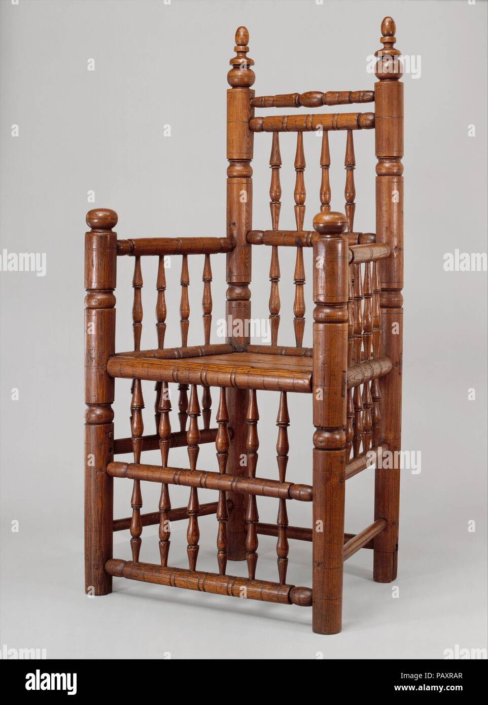 Spindle-back armchair. Culture: American. Dimensions: 44 3/4 x 23 1/2 x 15 3/4 in. (113.7 x 59.7 x 40 cm). Date: 1640-80.  The rarest and grandest of the early turned chairs are those with rows of spindles below the seat as well as above it. Although its boxlike form may look simple at first glance, this chair is a complex composition with subtle variations in the shaping of the rungs and in the spacing of its horizontal and vertical members. Museum: Metropolitan Museum of Art, New York, USA. Stock Photo