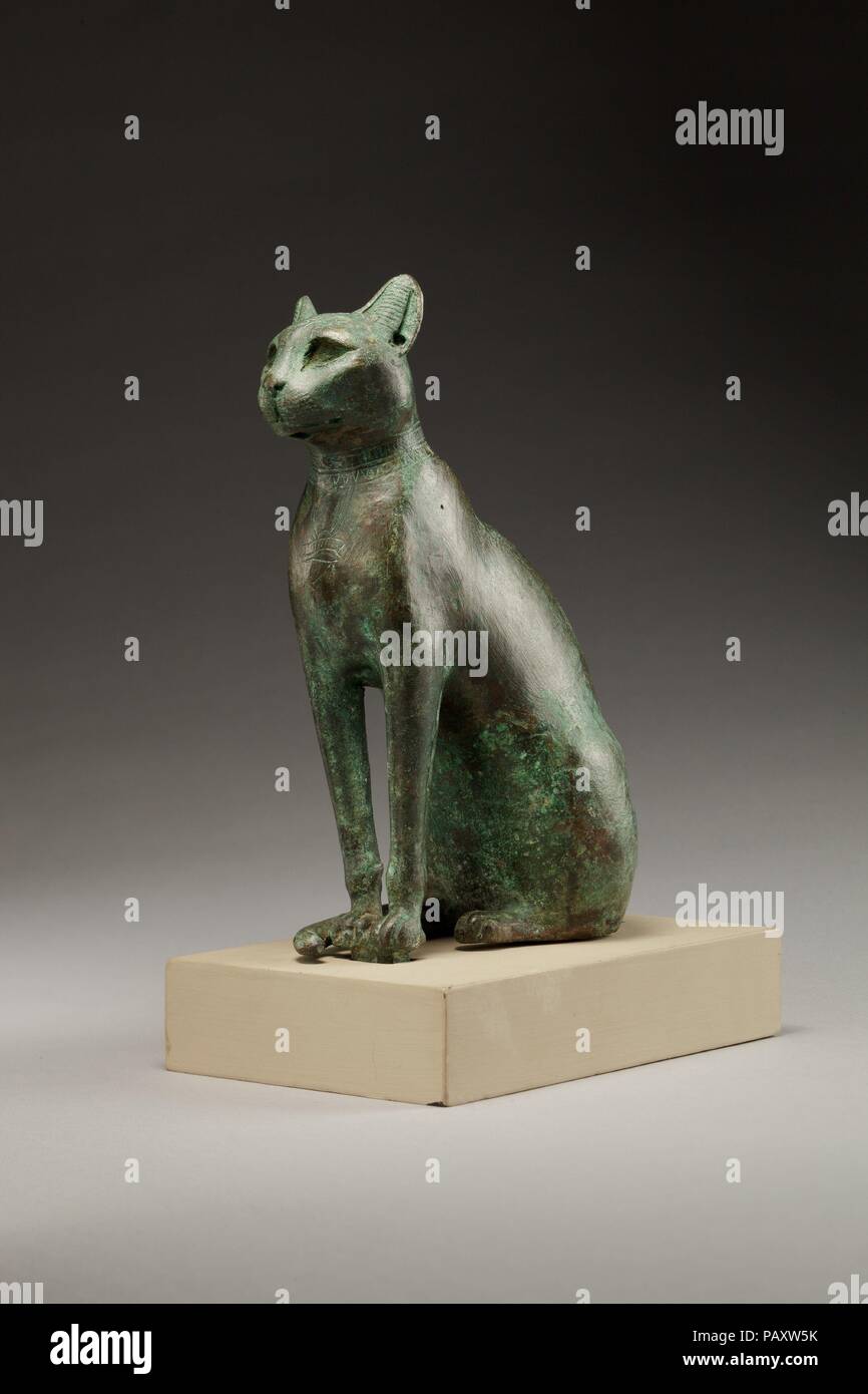 Cat. Dimensions: H. 15.8 cm (5 7/8 in.); W. 5.8 cm (2 5/16 in.); L. 11.5 cm (4 1/2 in.)  H. (with tang): 17.8 cm (6 5/8 in.). Date: 664-30 B.C..  Bastet was a powerful goddess of Lower Egypt, one who was protective and could bring about great prosperity. In zoomorphic form, she was represented as a cat and cats were considered sacred to her. As a cat, she is poised and alert, on guard against external forces.  Like cat-headed Bastet statuettes, these seated cats often have special adornments, but this figure is even more elaborate than most. It has deep-cut eyes for inlay and ears pierced for  Stock Photo