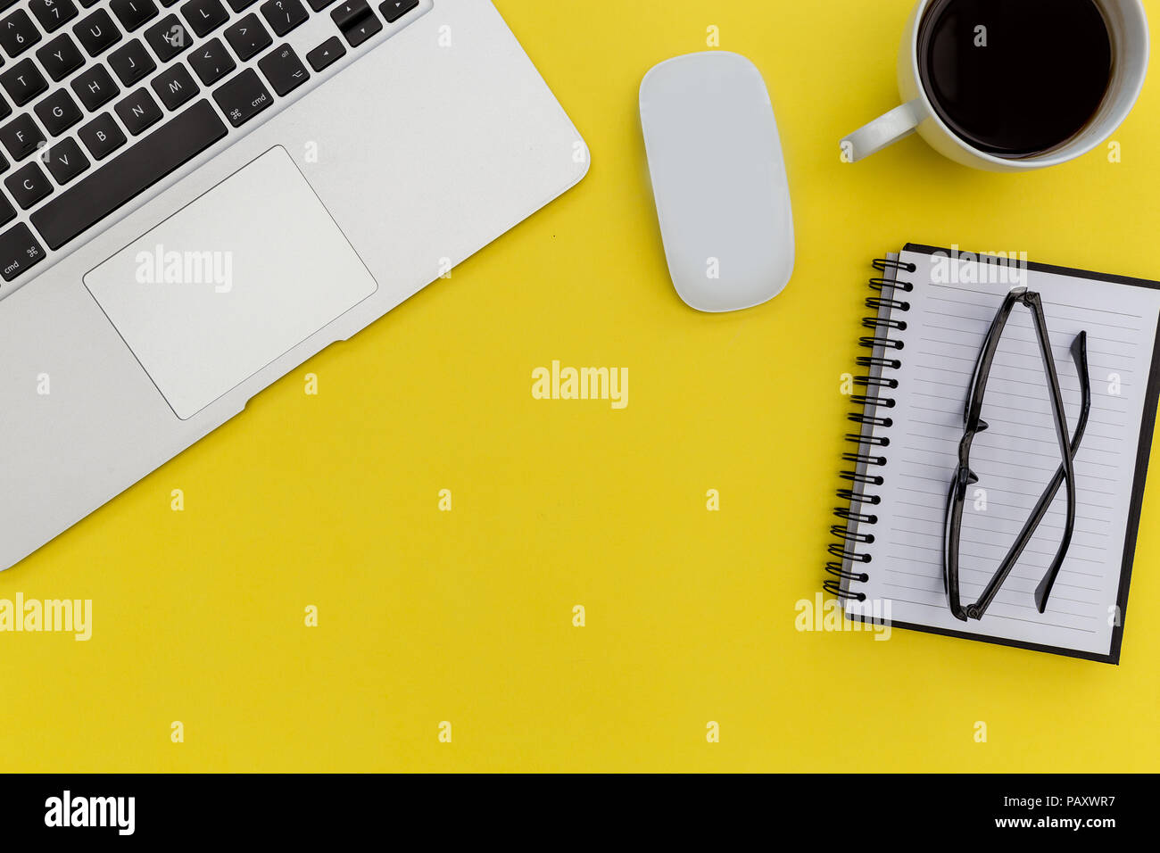 Laptop computer mouse and notebook on bright yellow background Stock Photo