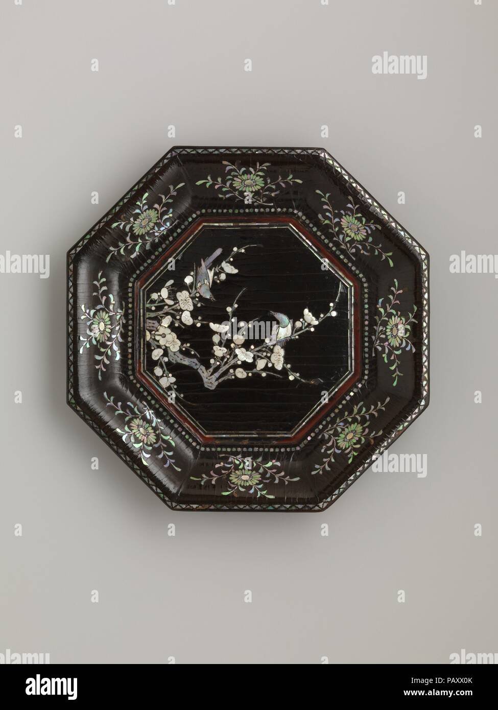 Dish with Flowering Plum and Birds. Culture: China. Dimensions: H. 1/8 in. (.3 cm); Diam.11 5/8 in. (29.5 cm). Date: 14th century.  Flowering plums and birds, possibly magpies, a popular theme in the paining and poetry of the Southern Song dynasty (1279-1368), were understood as harbingers of spring, because the plum is one of the first blossoms to appear as winter ends. This depiction of plum blossoms, which range from buds to full blooms, derives from the influential Manual of Plum Blossom Likeness (Meihua xishen pu), written by the artist Song Boren in the mid-thirteenth century, which disc Stock Photo
