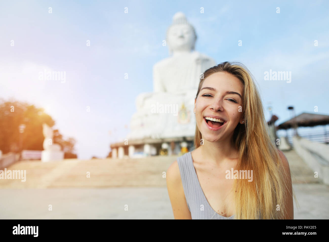 Young smiling girl near statue of Buddha in Phuket, Thailand. Stock Photo