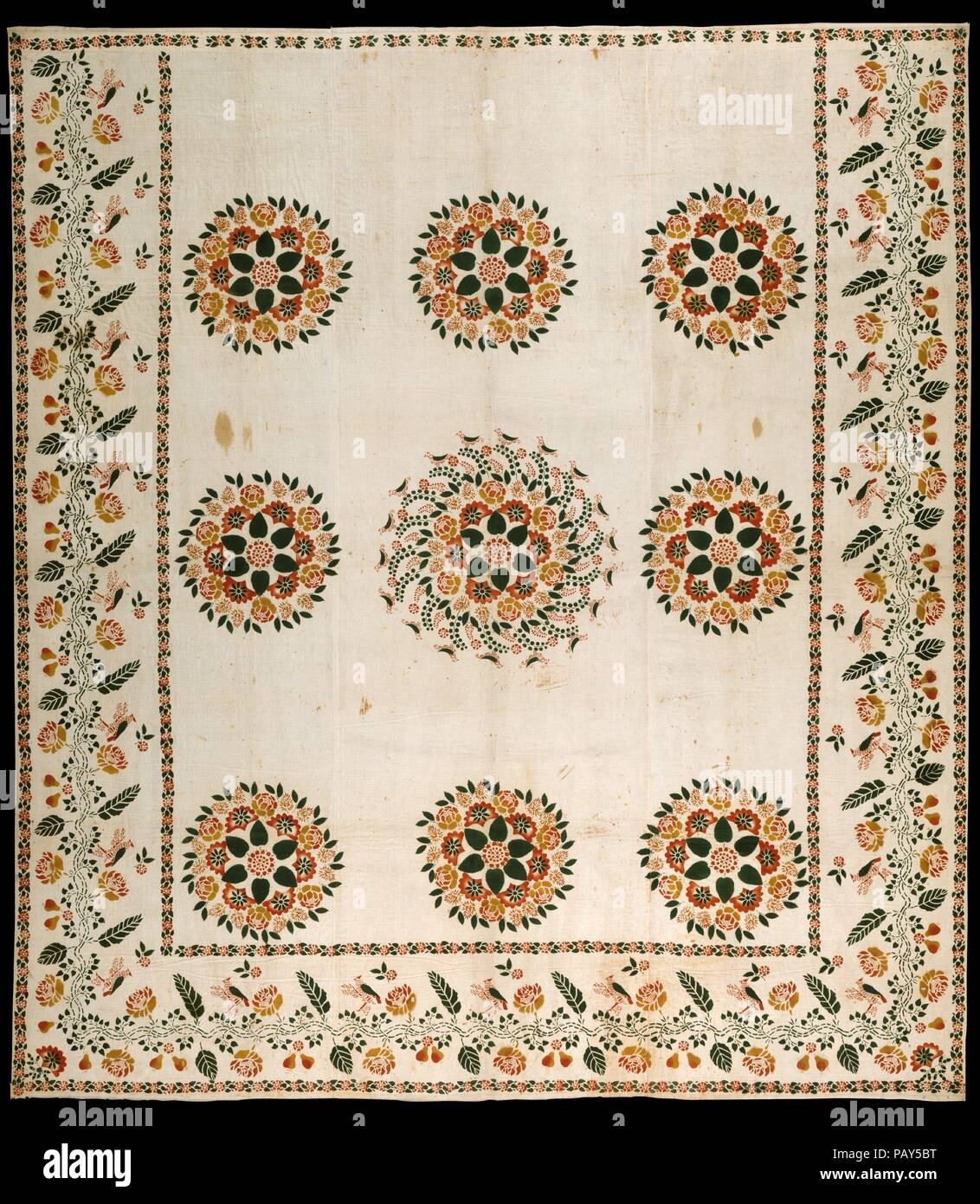 Wholecloth stenciled coverlet. Culture: American. Dimensions: 89 x 81 in. (226.1 x 205.7 cm). Date: ca. 1820-40.  This one-layer coverlet is made of three lengths of white cotton fabric that are seamed together. Red, yellow, and green paints are stenciled on the surface M a pattern of nine medallions with a surrounding border of flowers, fruit, and birds. Museum: Metropolitan Museum of Art, New York, USA. Stock Photo