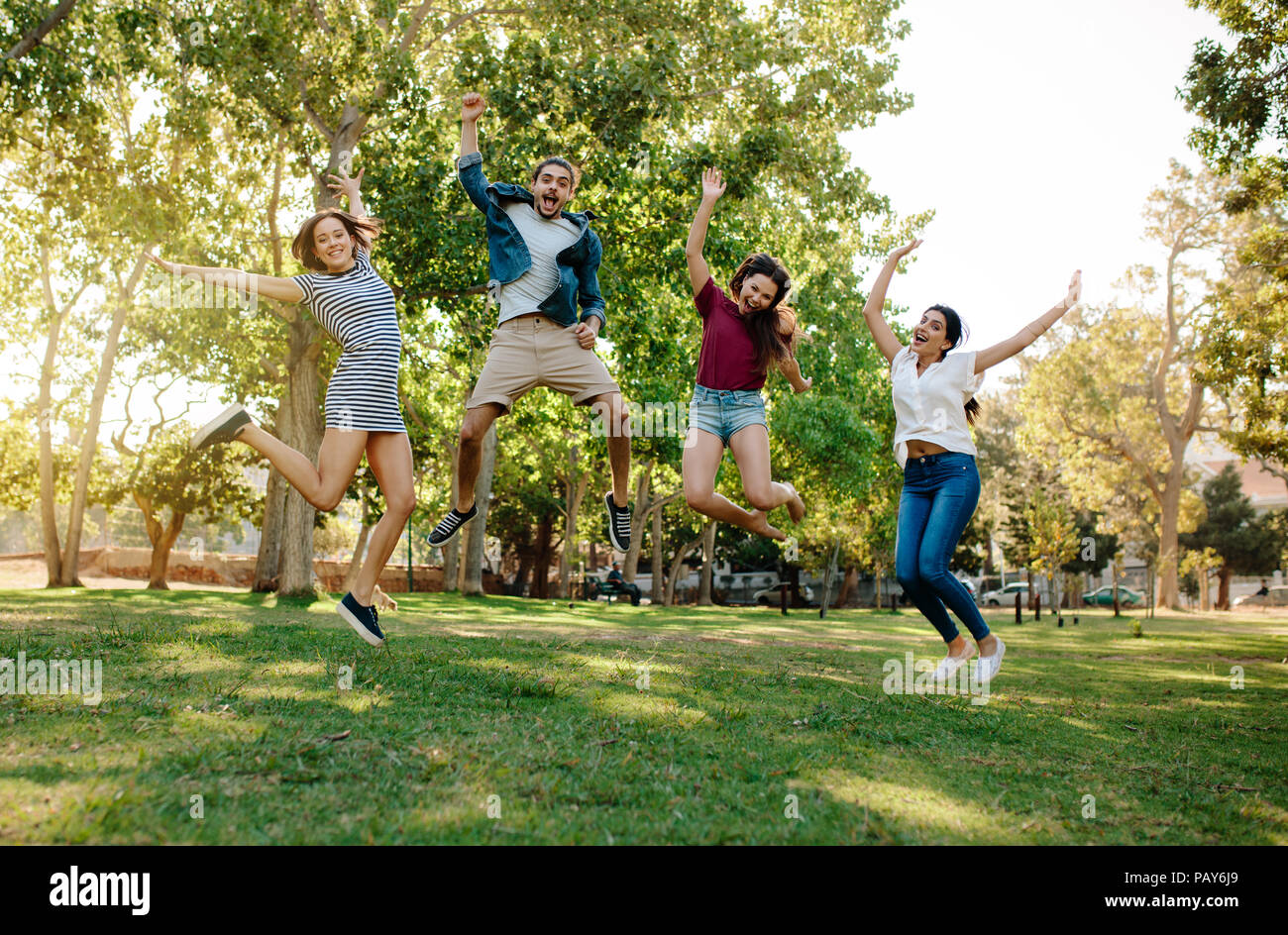 Group of young man and women jumping at the park. Friends enjoying at a park. Stock Photo