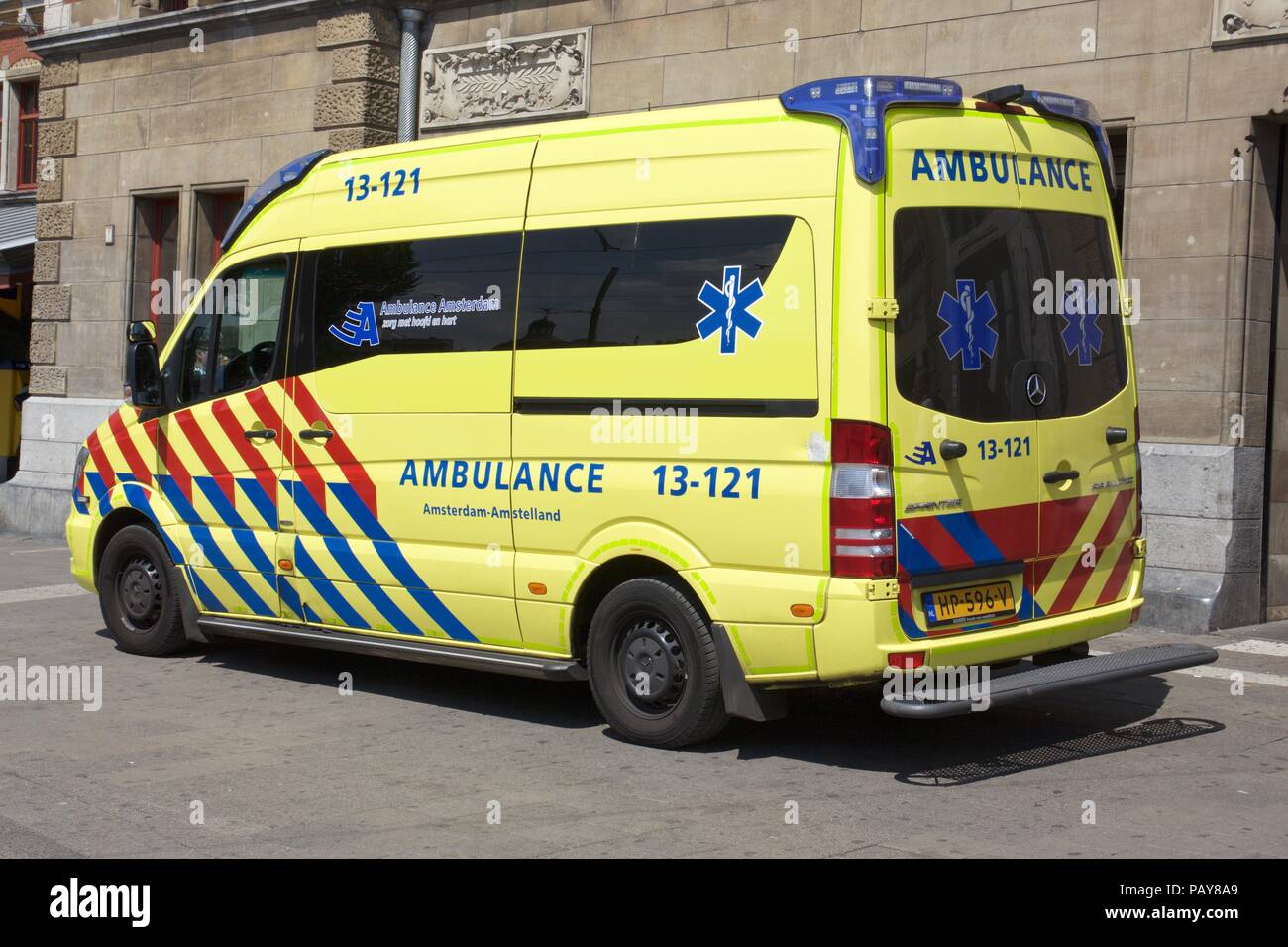 A yellow ambulance vehicle parked outside Amsterdam Centraal station, Amsterdam, The Netherlands Stock Photo
