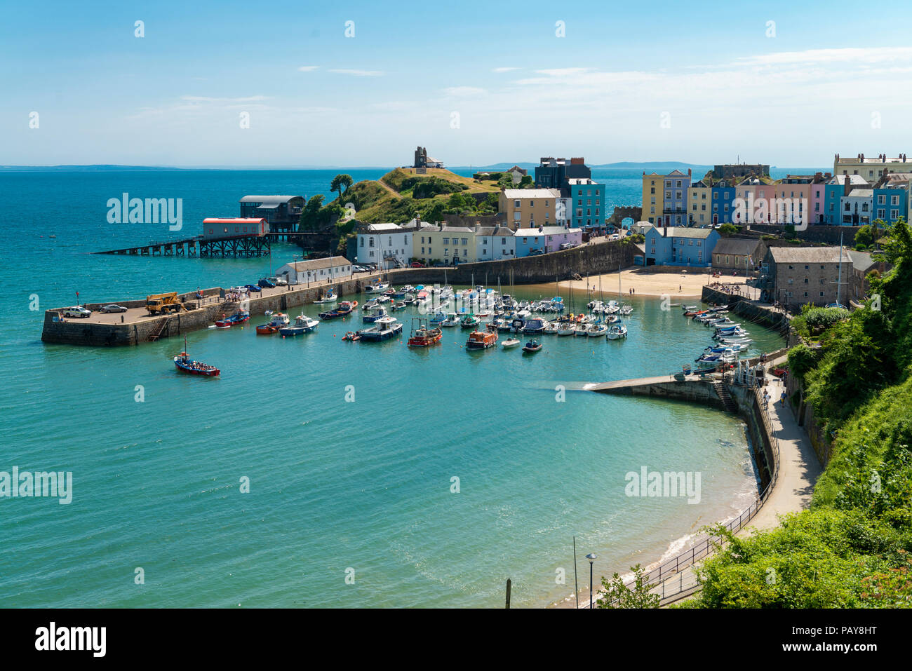 The pretty seaside town of Tenby, Pembrokeshire, Wales, UK looks stunning under a blue summer sky. Colourful  houses surround the harbour at high tide. Stock Photo