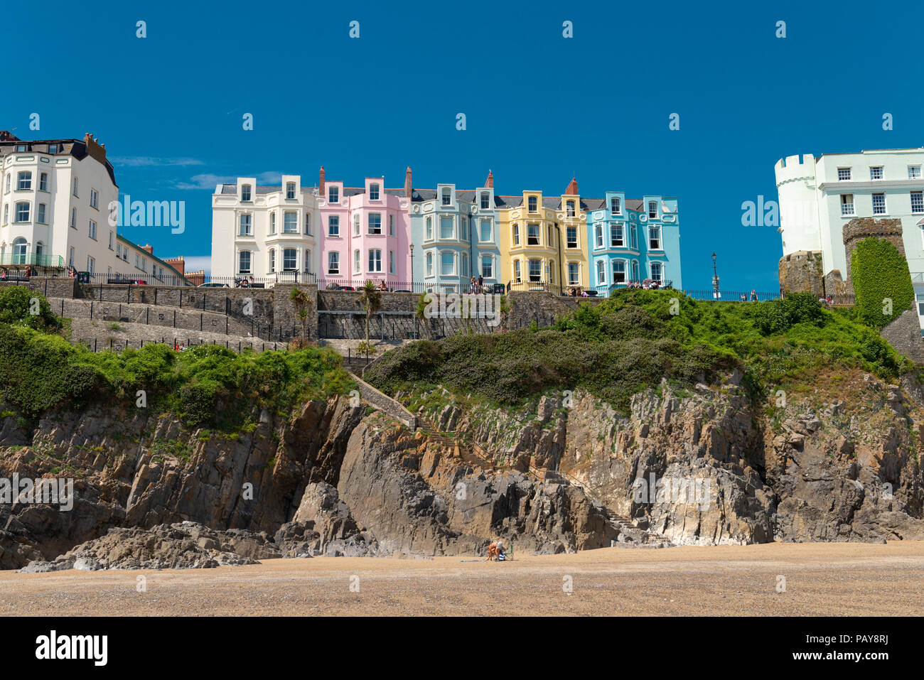Under a blue summer sky hotels and houses sit on the cliff overlooking South Beach in the pretty seaside town of Tenby, Pembrokeshire, Wales, UK. © Ro Stock Photo