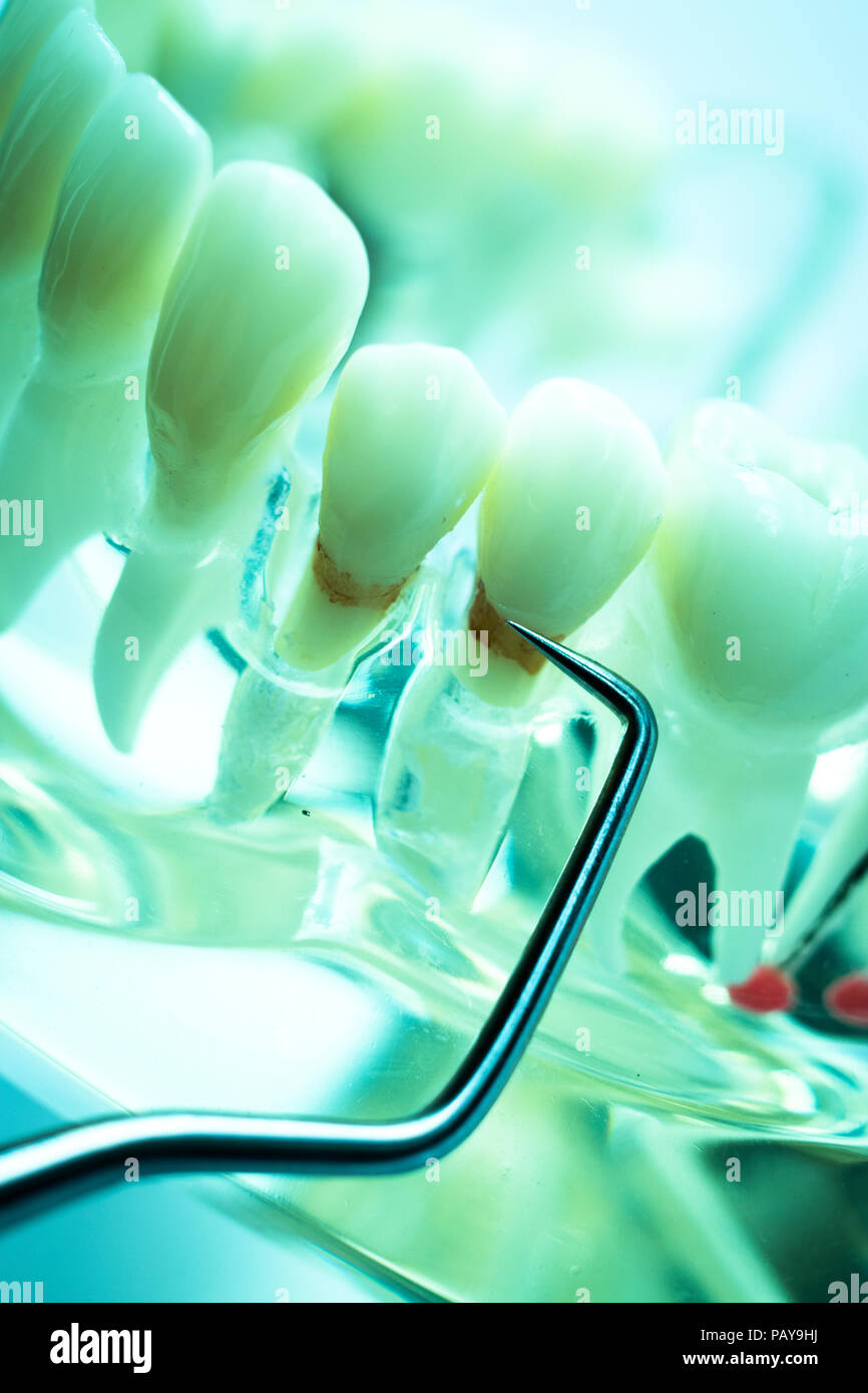 Dentist cleaning teeth with titanium metal tooth pick instrument to