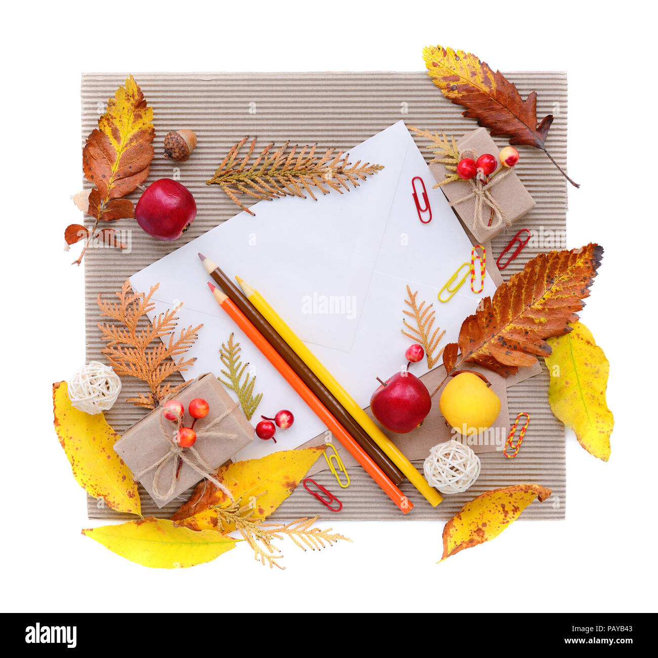 Autumn background with white envelope, colour pencils and autumn leaves on corrugated paper. Top view. Space for your text. Stock Photo