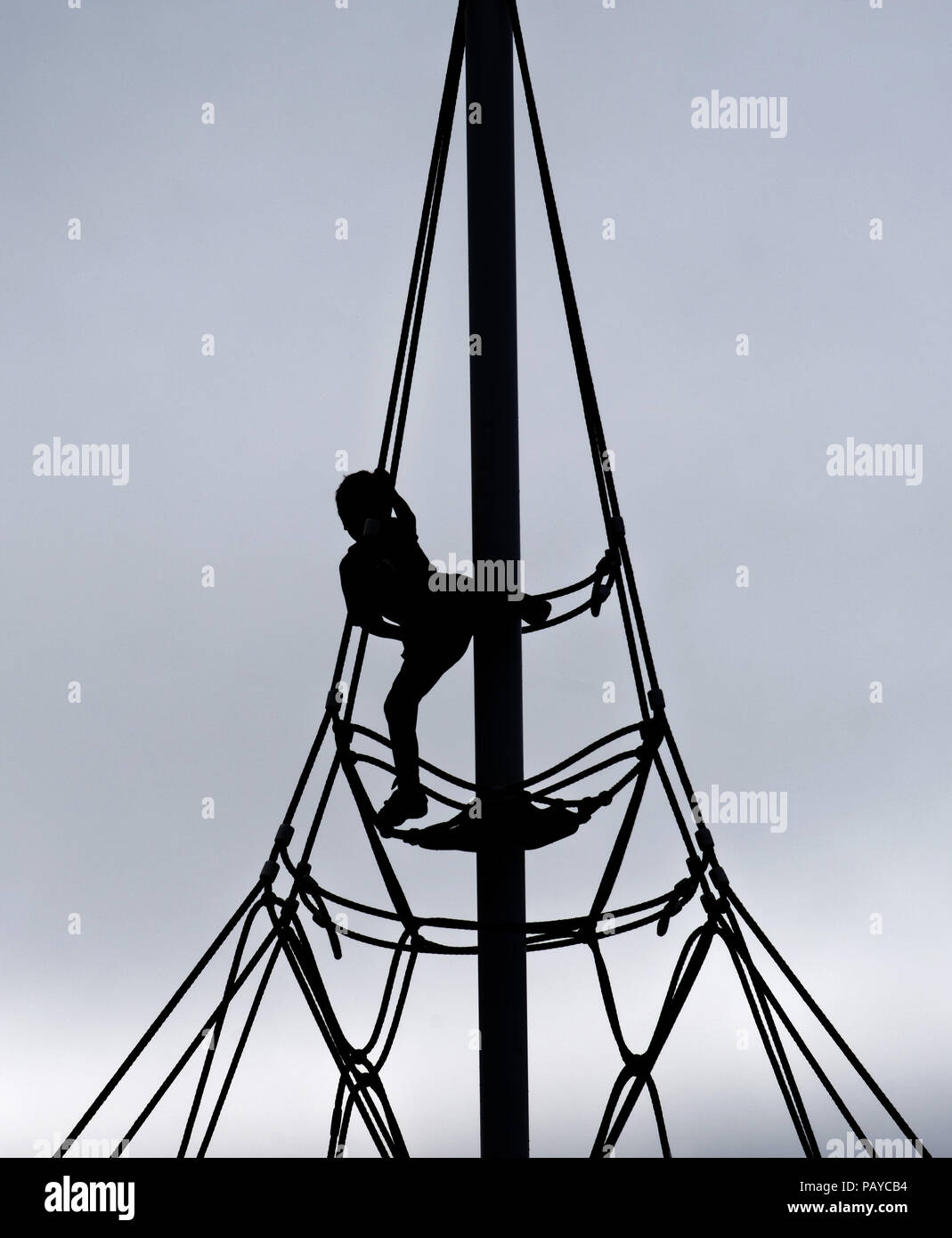 A silhouette of a young boy (6 yr old) on a rope climbing frame Stock Photo