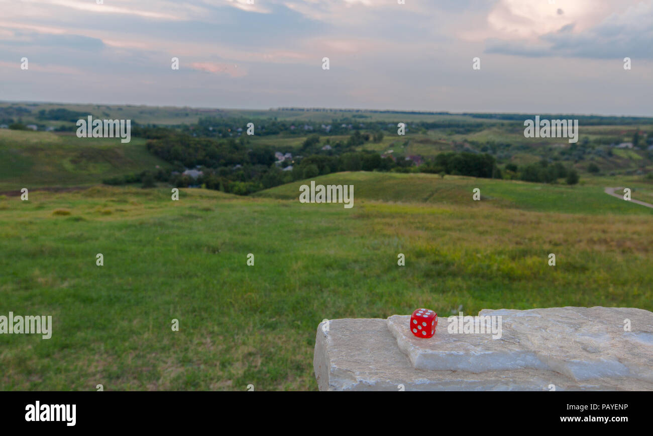 red dice lies on a granite on a grass hill background Stock Photo