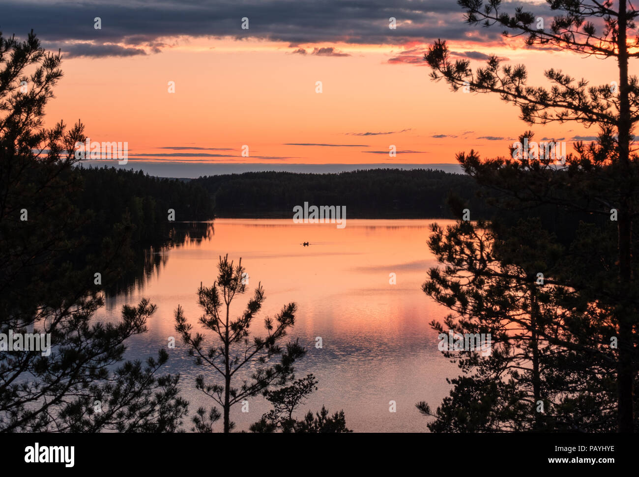 Sunset landscape with peaceful lake and row boat at summer night in Finland. Stock Photo