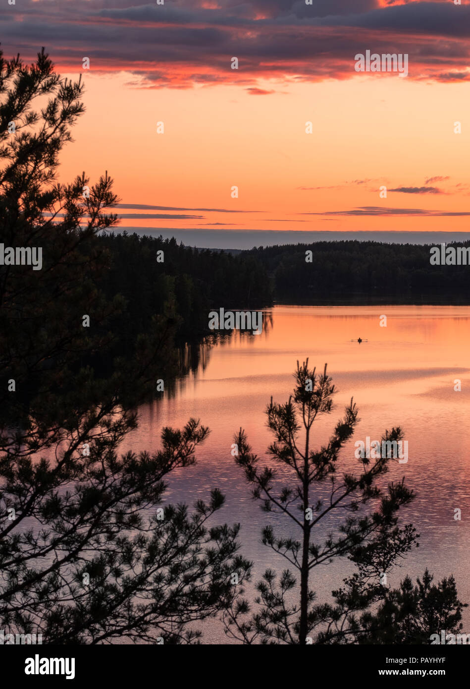 Sunset landscape with peaceful lake and row boat at summer night in Finland. Stock Photo