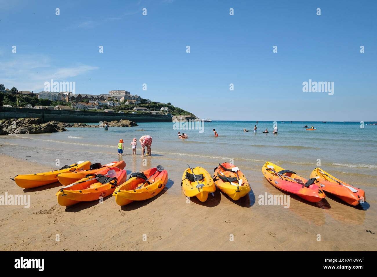 a row of brightly coloured kayaks on the beach at Newquay in Cornwall