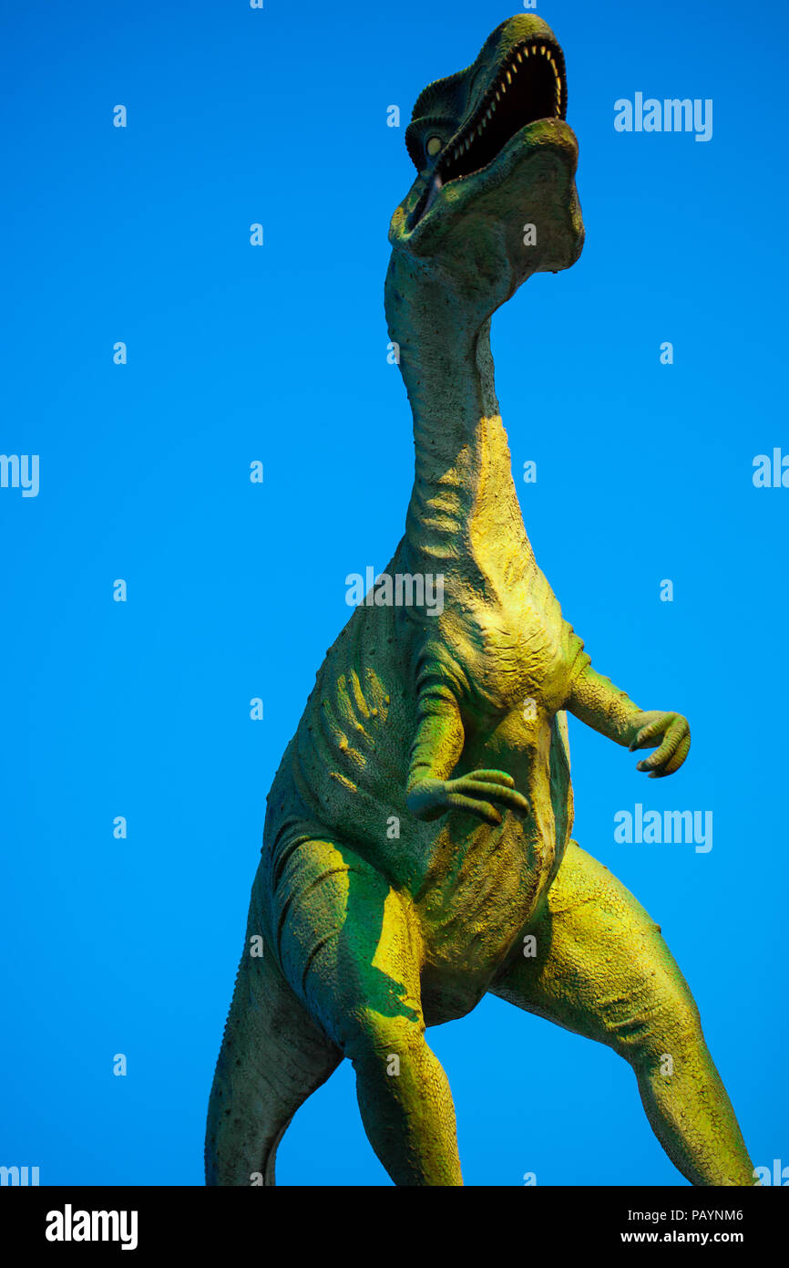 Model of Velociraptor roaring against blue sky Stock Photo