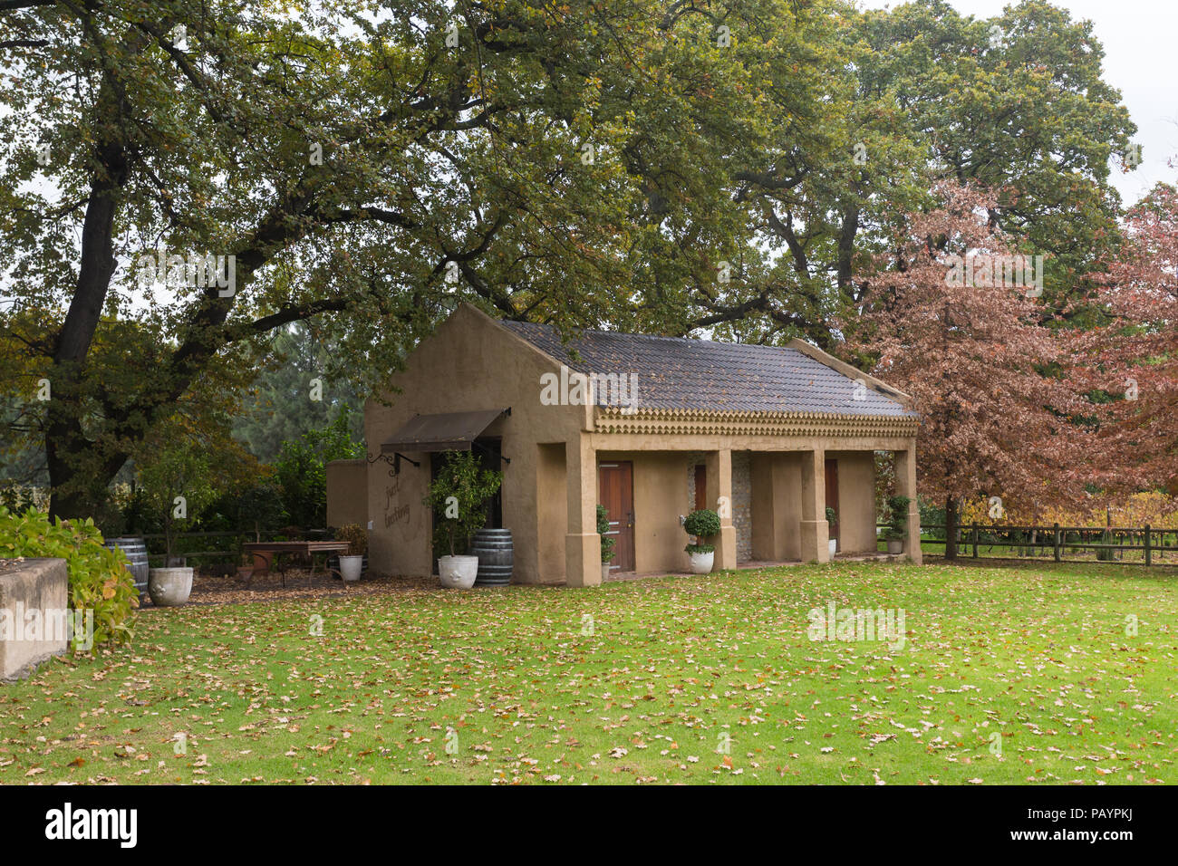 Autumn or Fall landscape scene of small cottage or building used as wine tasting centre set in large garden with trees as background and decor items Stock Photo