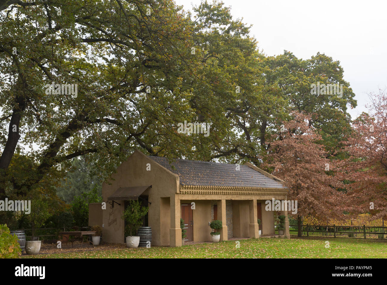 Autumn or Fall landscape scene of small cottage or building used as wine tasting centre set in large garden with trees as background and decor items Stock Photo