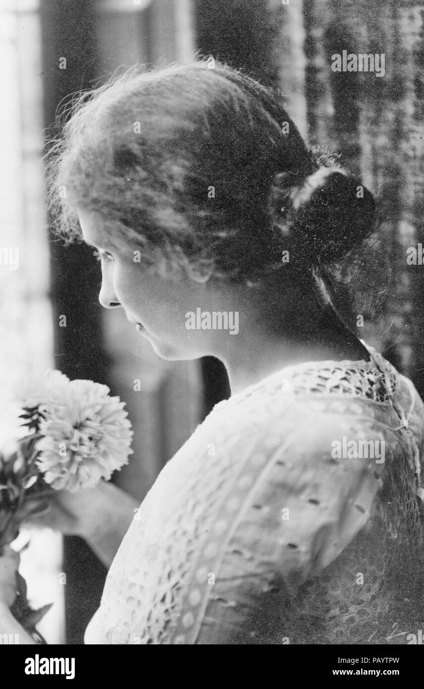 Helen Keller, head-and-shoulders portrait, facing left, holding flowers, circa 1912 Stock Photo