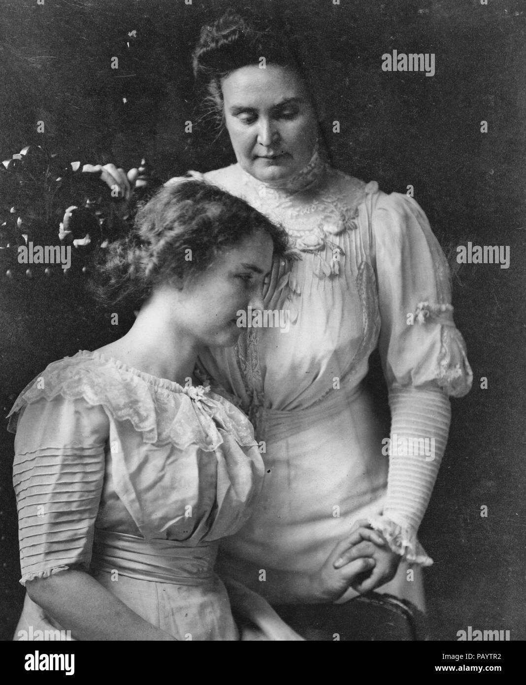 Helen Keller, three-quarter length, seated, facing right; holding hand of her teacher, Mrs. John A. Macy (Anne Mansfield Sullivan), circa 1909 Stock Photo