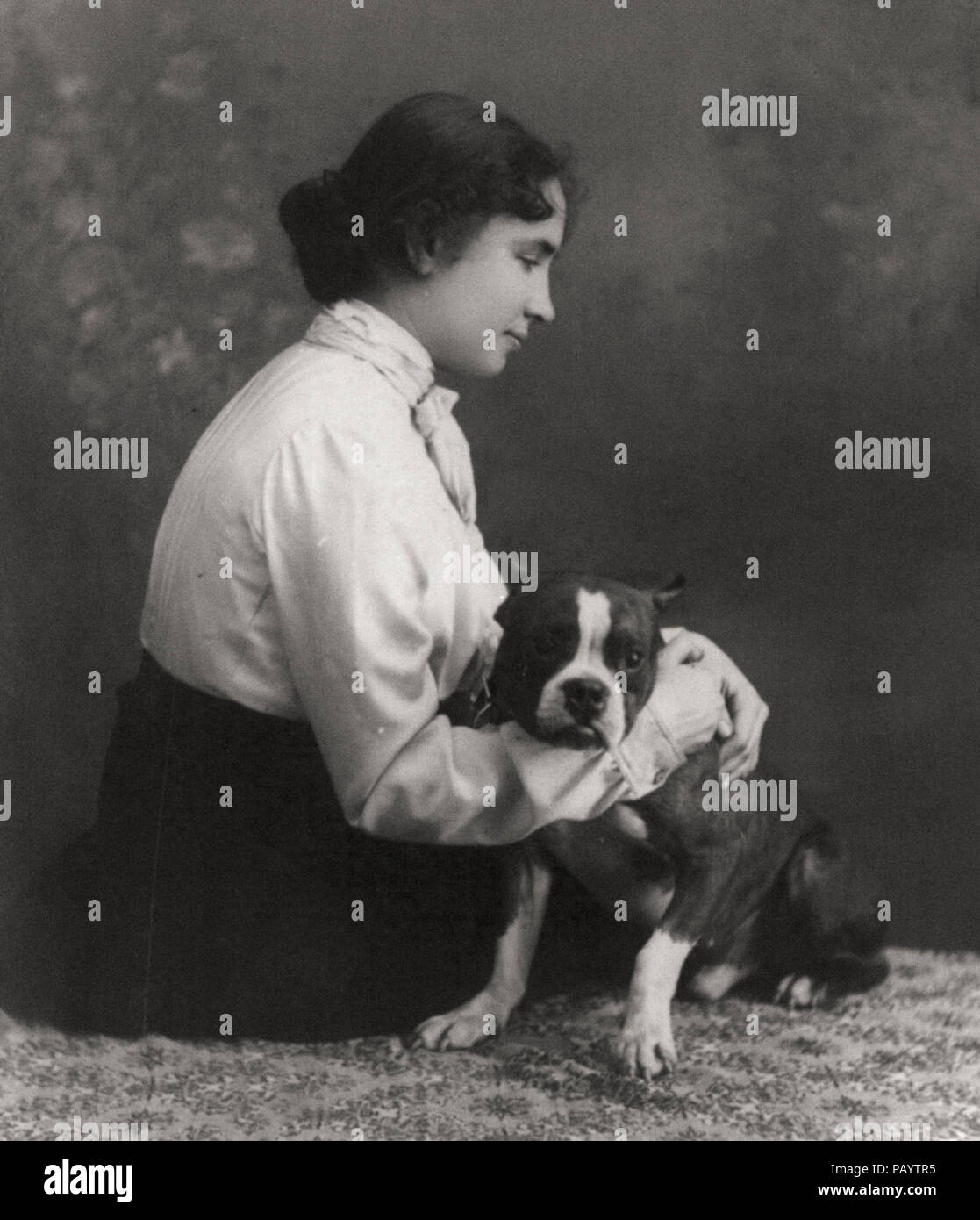 Helen Keller Portrait, three-quarter length., seated on floor, right profile; with arms around dog, circa 1902 Stock Photo