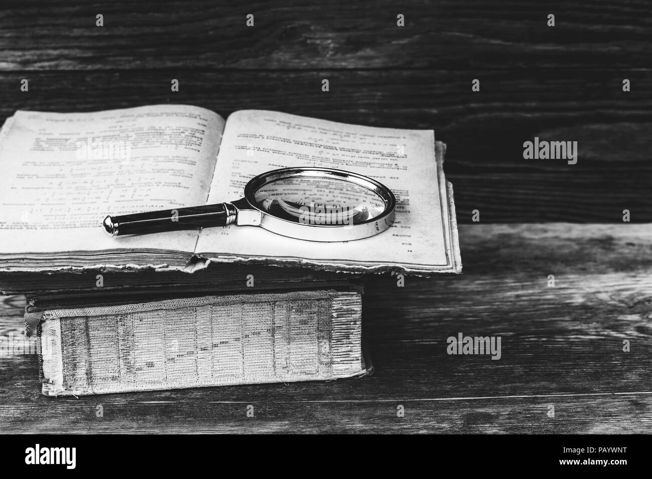 magnifying glass on old open book closeup photo Stock Photo - Alamy