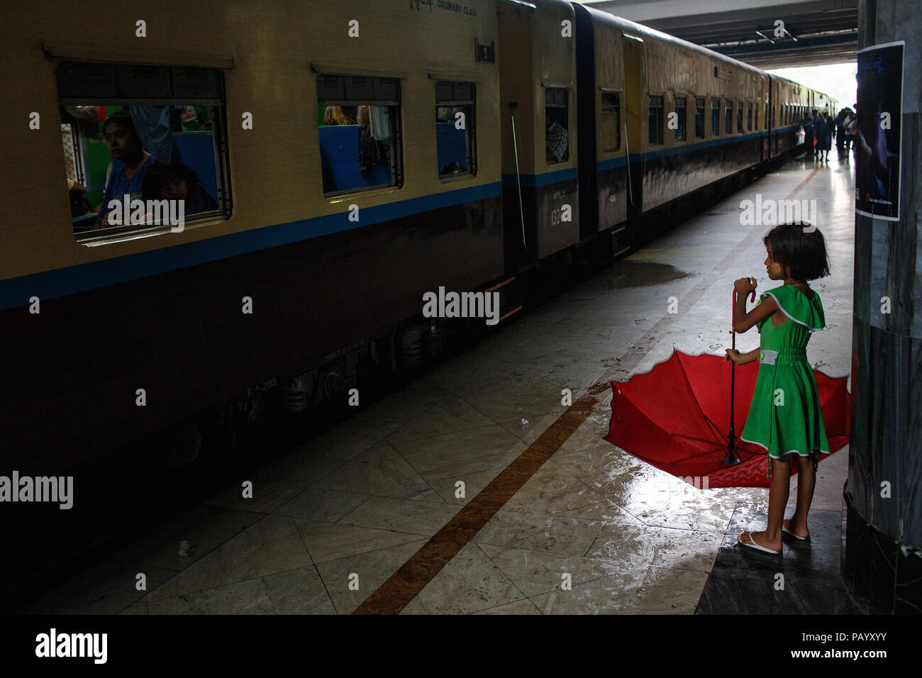 A young girl with an umbrella at the Railway Station in Mandalay, Myanmar. Stock Photo