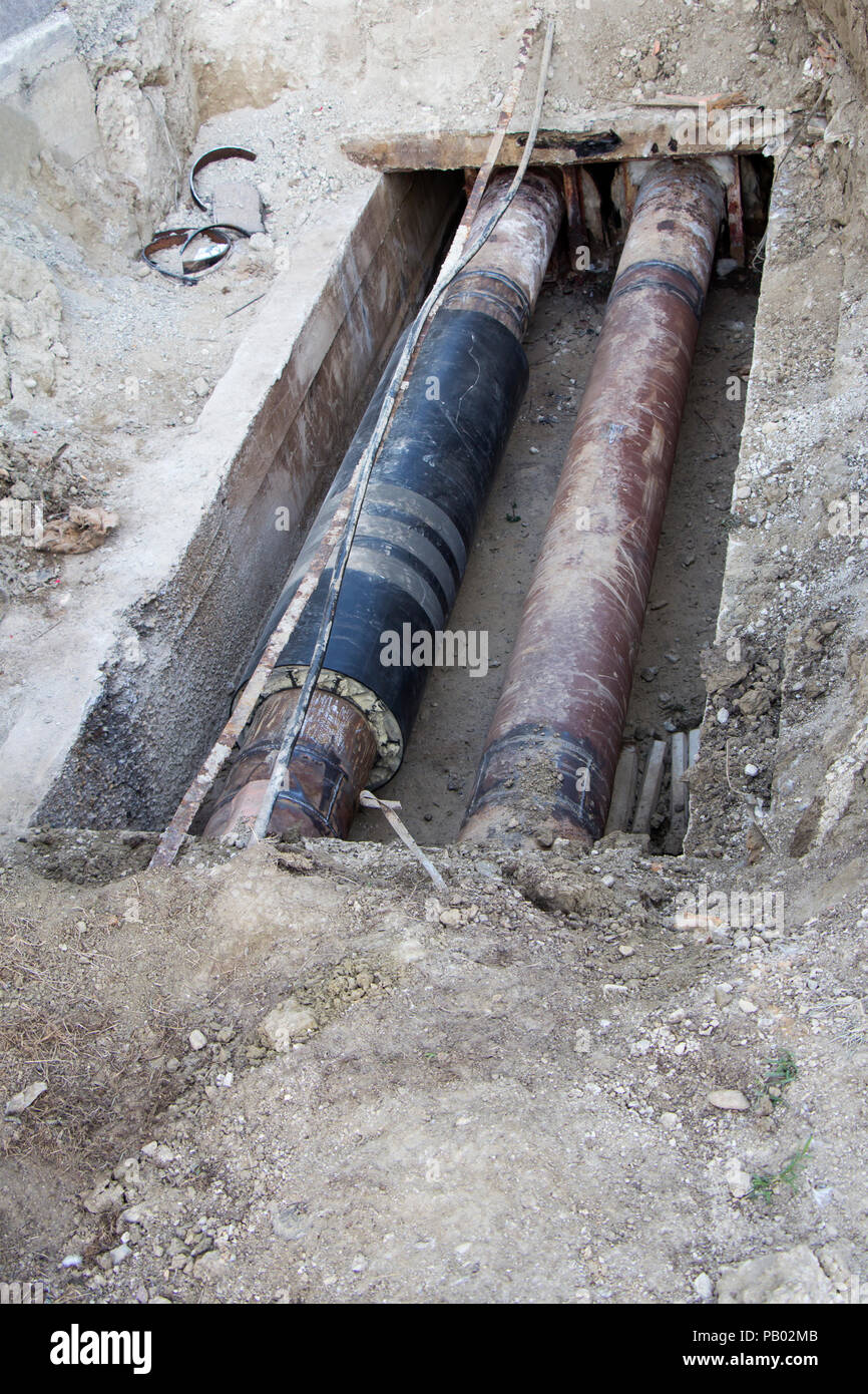 Repair of heating pipes at a depth of excavated trench Stock Photo