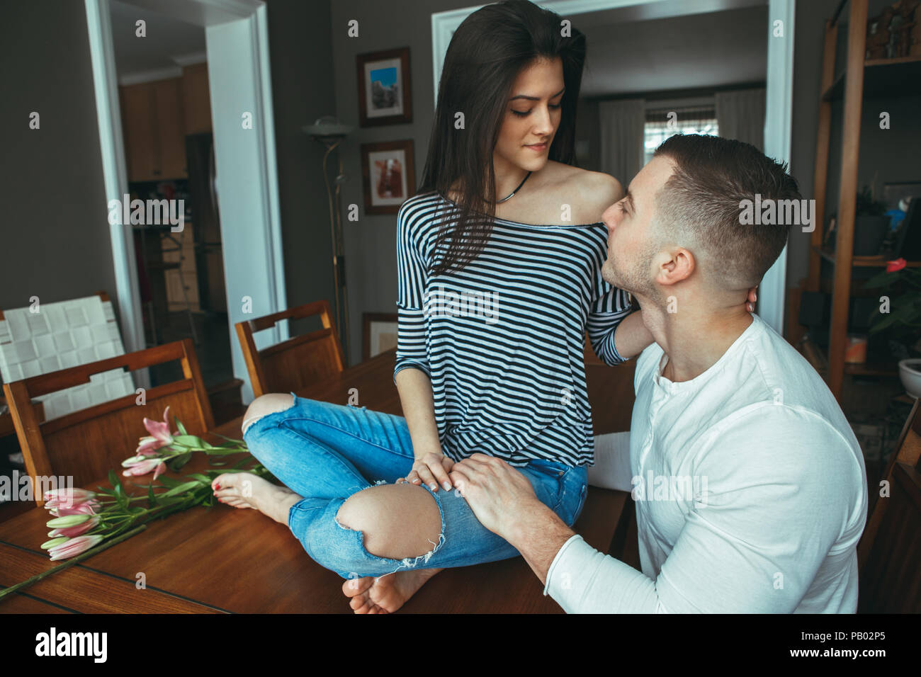 Portrait of beautiful romantic young couple man woman in love looking at each other indoors at home, toned with filters,  lifestyle candid Stock Photo
