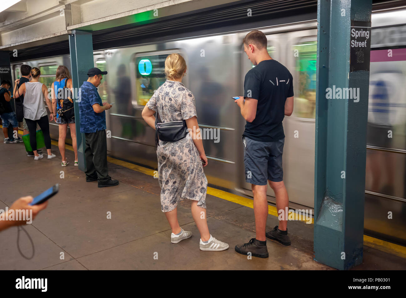 Weekend subway riders wait for a train at the Spring Street station in the New York subway on Saturday, July 14, 2018. (Â© Richard B. Levine) Stock Photo