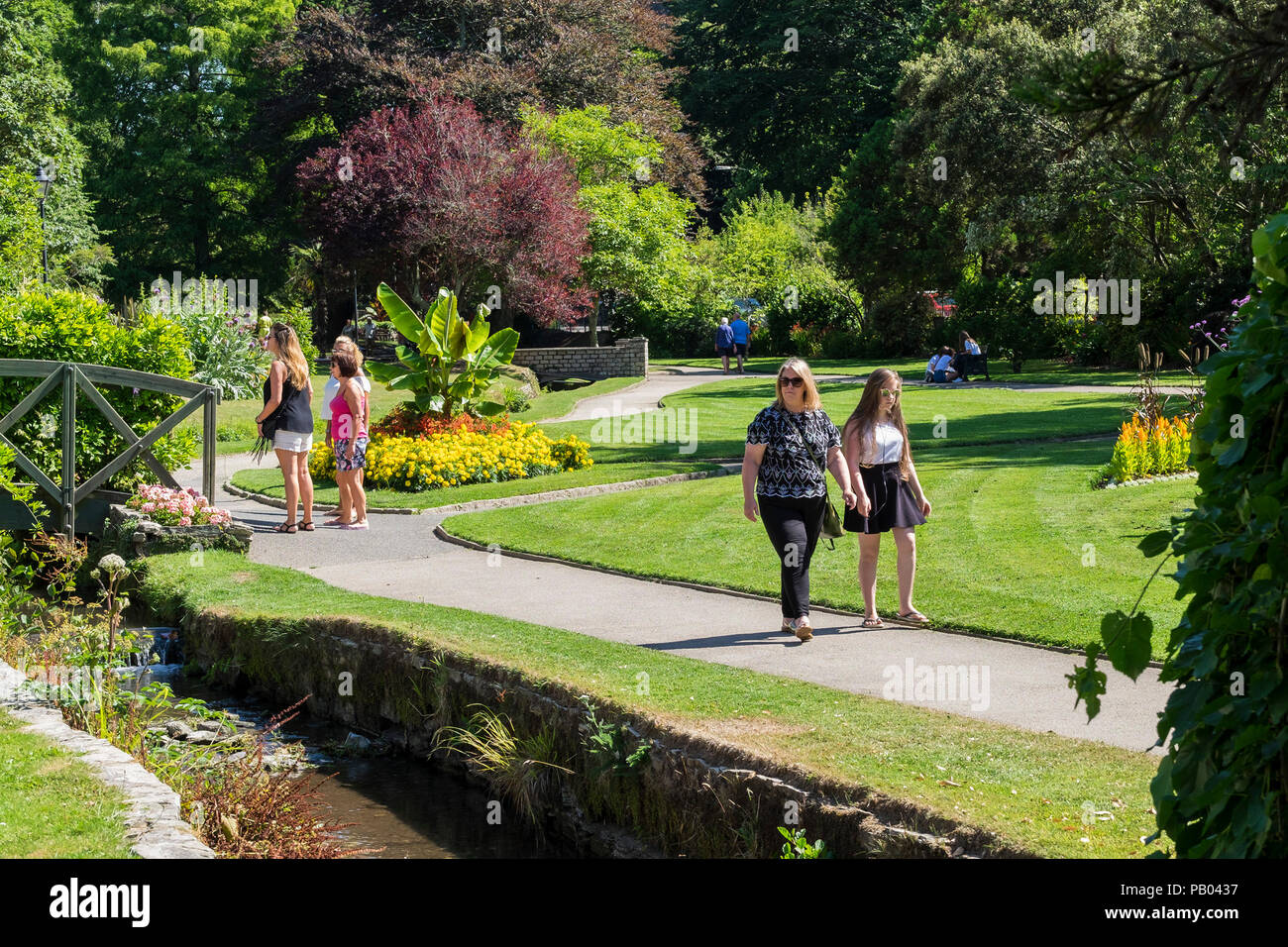 Holidaymakers enjoying a stroll in the sunny award winning Trenance Garden in Newquay Cornwall. Stock Photo