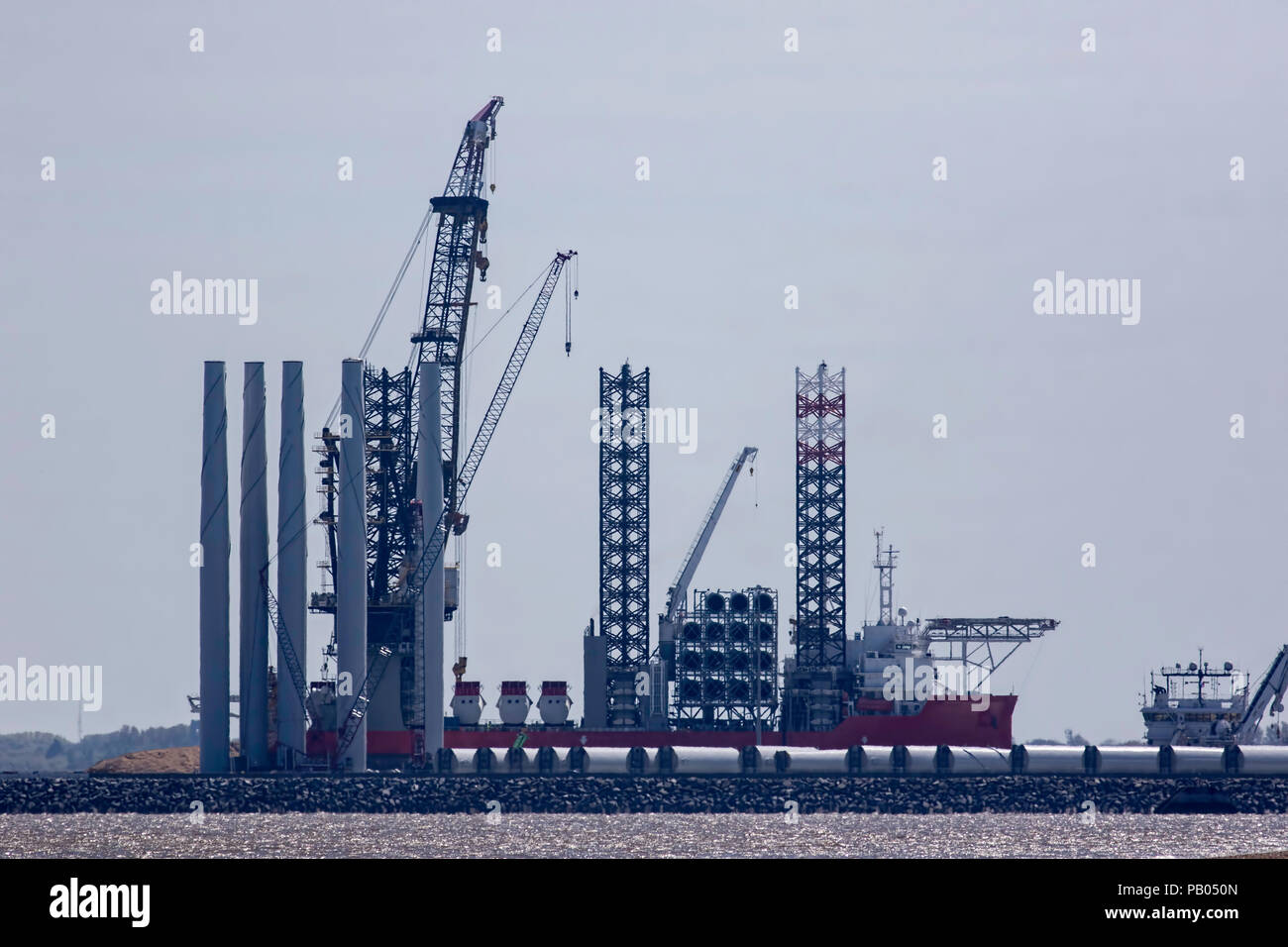 Offshore wind farm construction. Investment in renewable clean energy as a supply vessel ship is docked and ready to receive wind turbine parts. Stock Photo