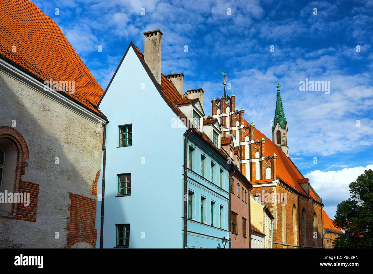 Latvia. The original medieval house with a tall chimney and a church ...