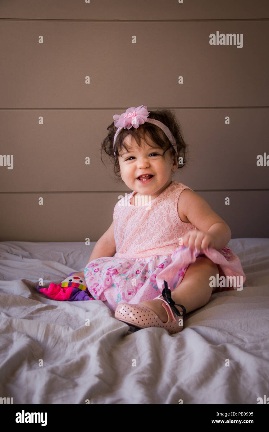 Portrait of a smiling girl sitting on a bed Stock Photo - Alamy