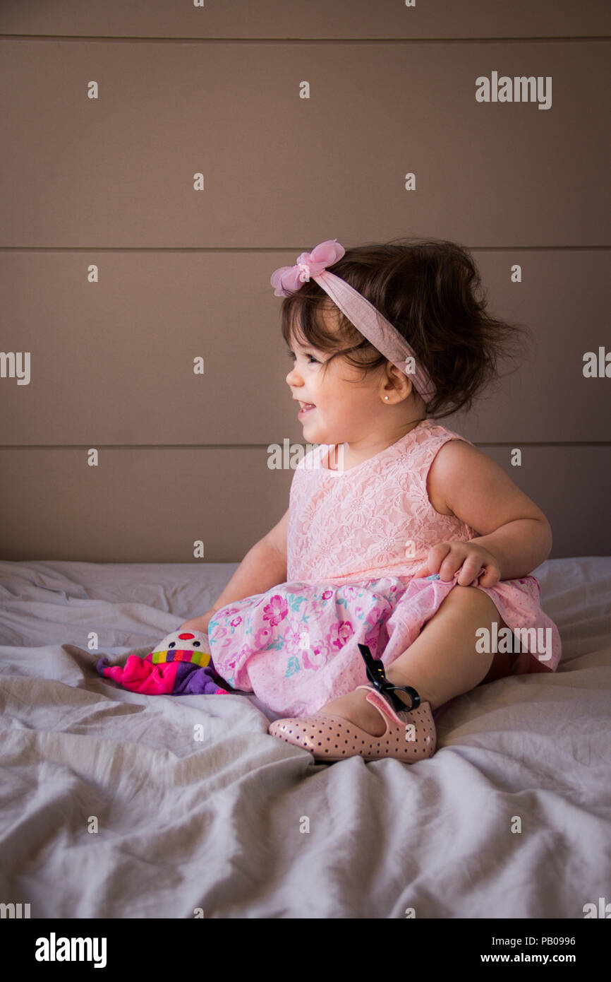 Portrait of a smiling girl sitting on a bed Stock Photo - Alamy