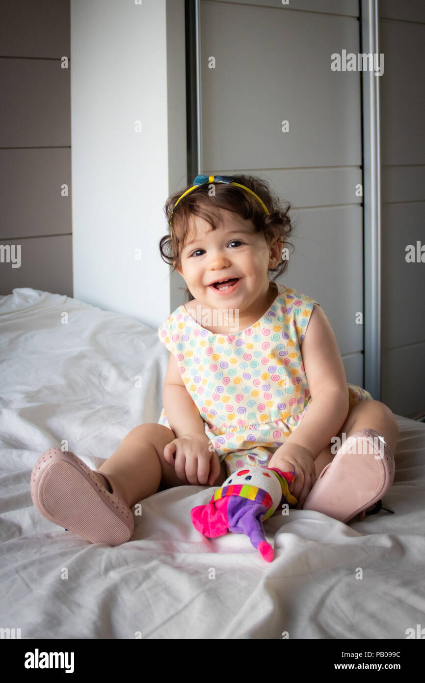 Portrait of a smiling girl sitting on a bed Stock Photo - Alamy
