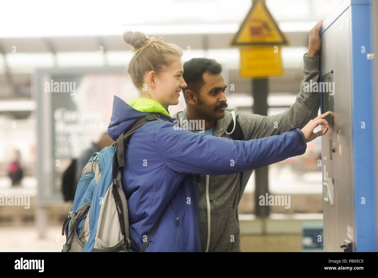 Couple at a train station buying a ticket from a ticket machine Stock ...