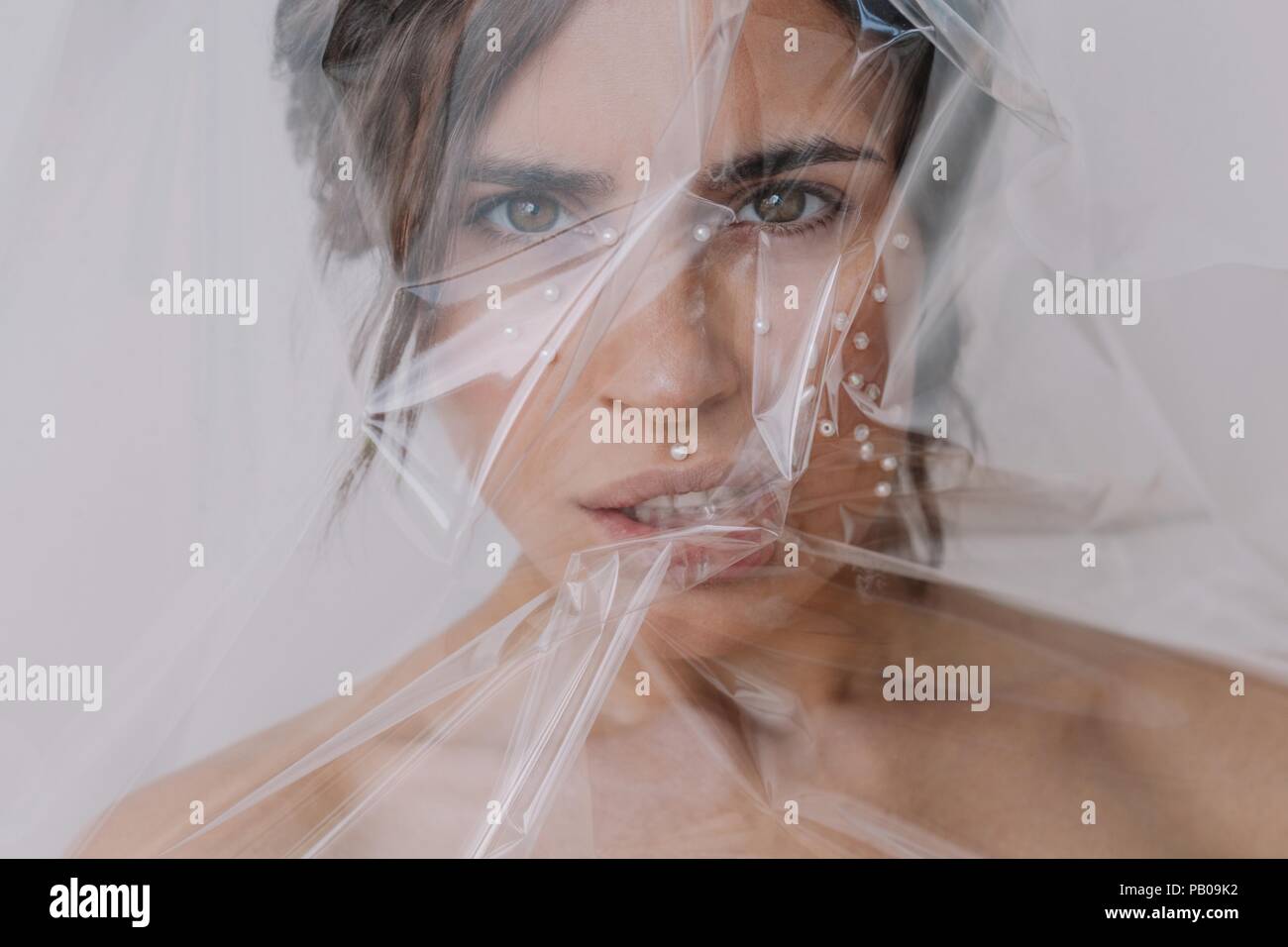 Portrait of a woman with pearls on her face wrapped in transparent plastic Stock Photo