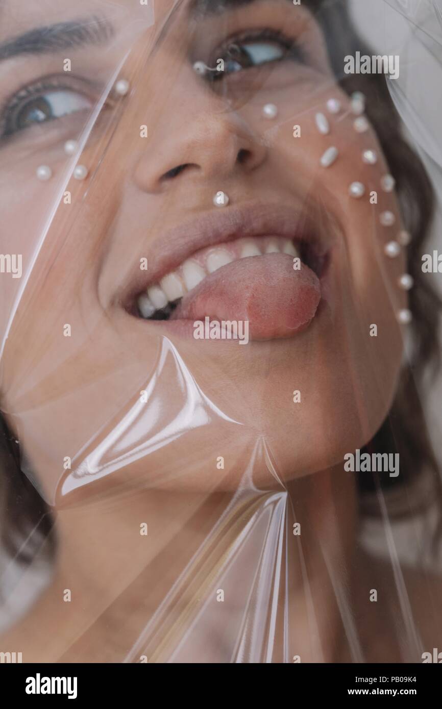 Portrait of a woman with pearls on her face wrapped in transparent plastic Stock Photo