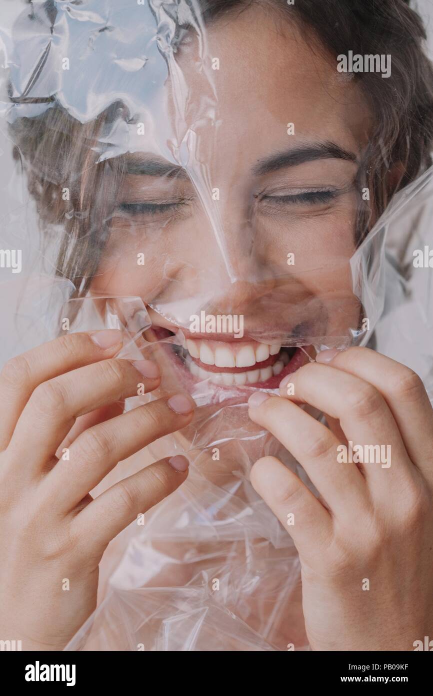 Portrait of a cheerful woman tearing plastic off her face Stock Photo