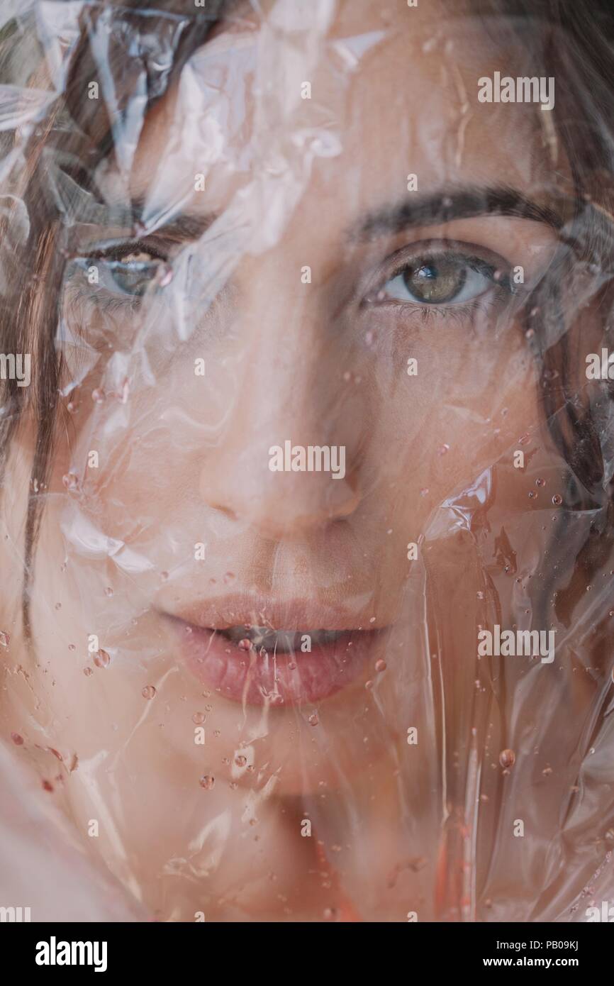 Woman looking through wet transparent plastic Stock Photo