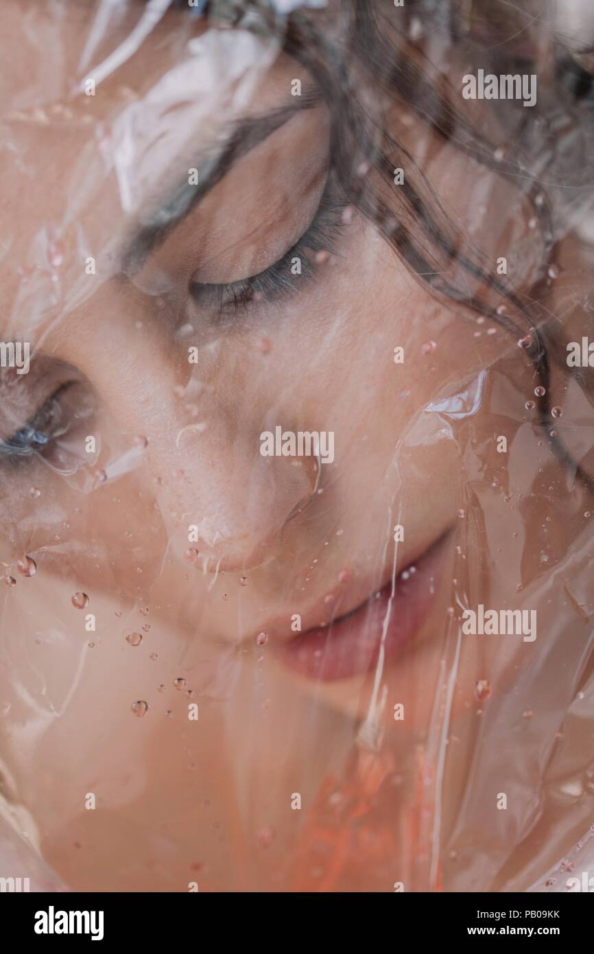 Woman looking through wet transparent plastic Stock Photo