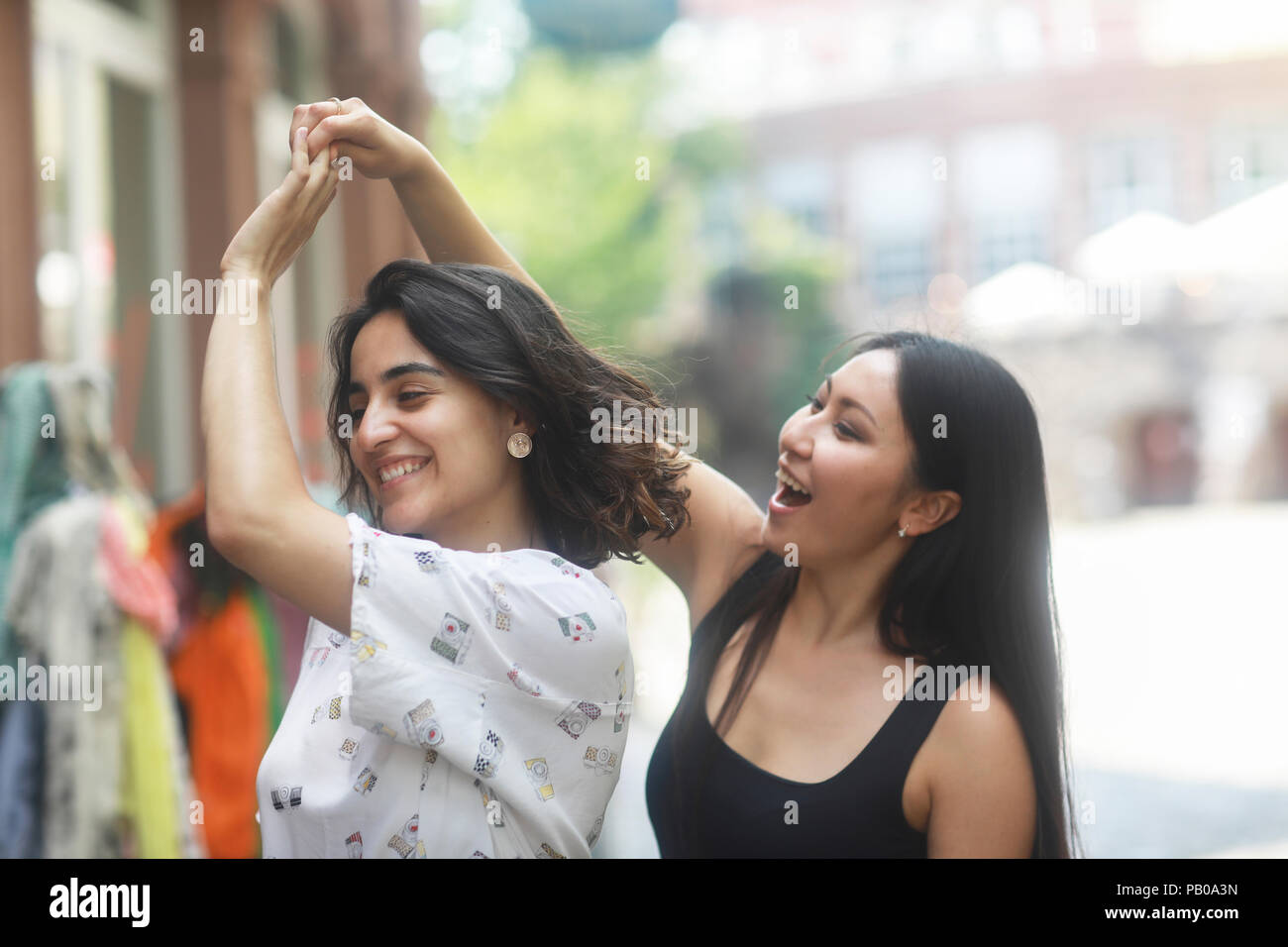 Two women standing outside a shop dancing Stock Photo