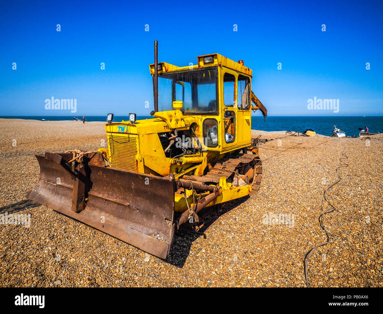 Aldeburgh Beach - a bulldozer prepares to pull a fishing boat up the shingle beach in Aldeburgh Suffolk UK Stock Photo