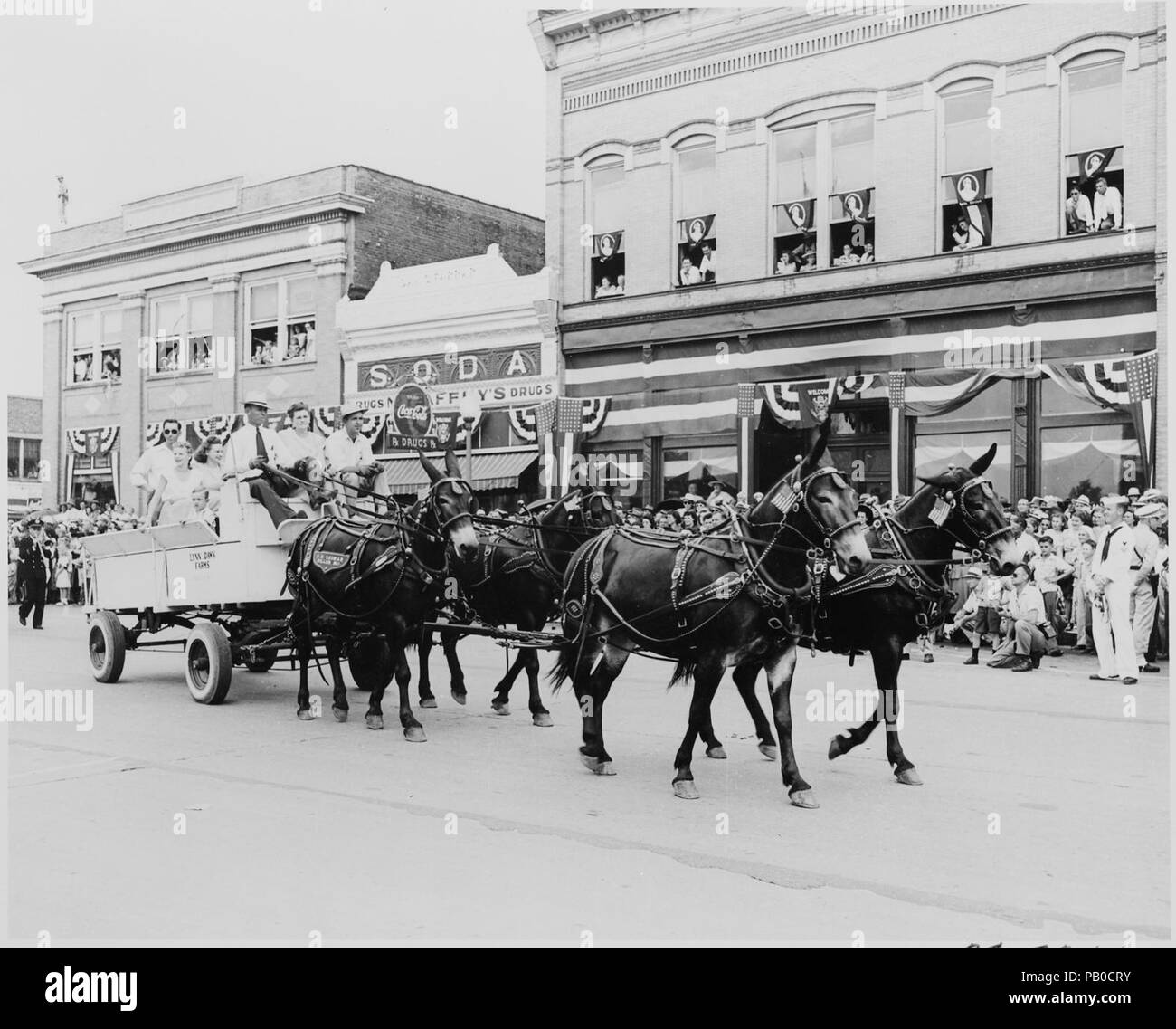 A wagon pulled by four mules, passing before a reviewing stand (not ...