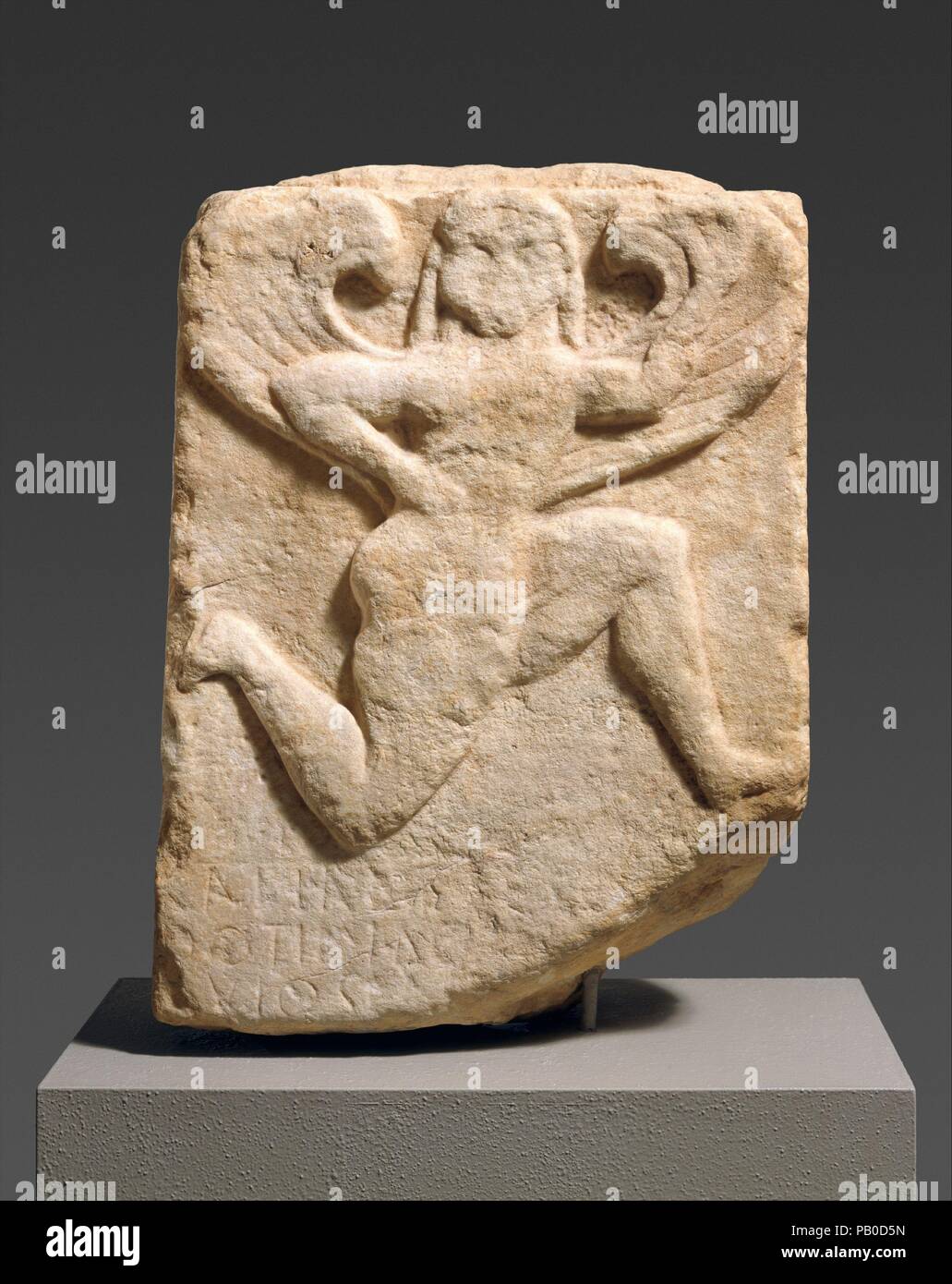 Part of the marble stele (grave marker) of Kalliades. Culture: Greek, Attic. Dimensions: 21 1/2in. (54.6cm)  Other (height without tenon): 20 7/8 in. (53 cm)  Other (median thickness): 6 in. × 15 3/4 in. (15.2 × 40 cm)  Width (top): 14 3/4 in. (37.5 cm)  Width (bottom): 15 9/16 in. (39.5 cm). Date: 550-525 BC.  A fleeing Gorgon decorates this tapering, predella-looking slab, part of the grave stele of Kalliades, as we learn from the inscription carved in three lines from left to right below the Gorgon's left knee: 'Kalliades, son of Thoutimides'.  The Gorgon, dressed in a short chiton, spreads Stock Photo