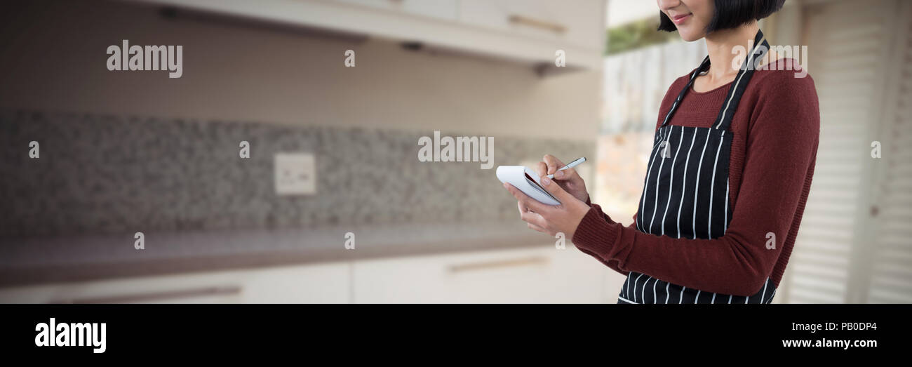 Composite image of smiling waitress writing order on notepad Stock Photo