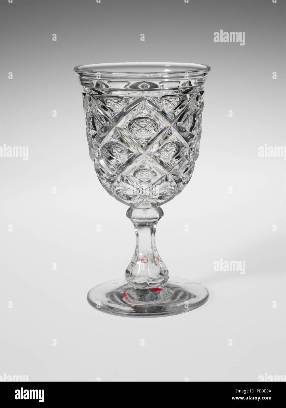 Goblet. Culture: American. Dimensions: H. 6 7/16 in. (16.4 cm); Diam. 3 5/16 in. (8.4 cm). Date: 1850-60.  With the development of new formulas and techniques, glass-pressing technology had improved markedly by the late 1840s. By this time, pressed tablewares were being produced in large matching sets and innumerable forms. During the mid-1850s, colorless glass and simple geometric patterns dominated. Catering to the demand for moderately-priced dining wares, the glass industry in the United States expanded widely, and numerous factories supplied less expensive pressed glassware to the growing Stock Photo