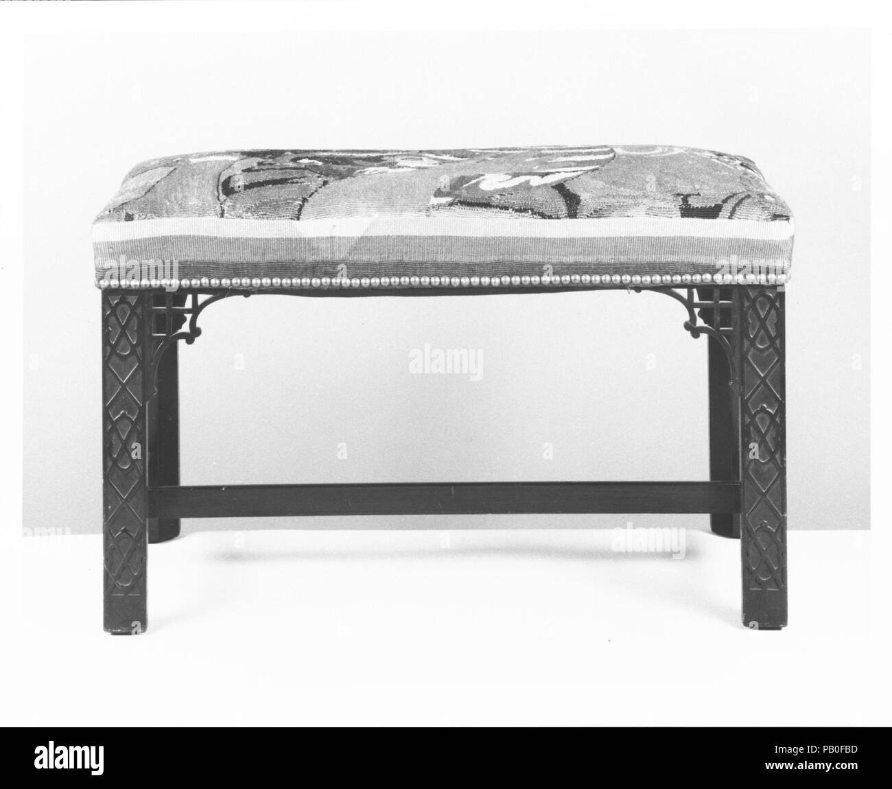 Bench. Culture: American. Designer: Designed by Louis Comfort Tiffany (American, New York 1848-1933 New York). Dimensions: 17 1/2 x 27 1/2 x 16 11/16 in. (44.5 x 69.9 x 42.4 cm). Maker: Tiffany Studios (1902-32). Date: 1916.  Thomas Chippendale's influential book of furniture designs, 'The Gentleman and Cabinetmaker's Director' (London, 1754), tapped into the growing interest in Chinese ornament in England and the colonies. More than one hundred years later, Chippendale's furniture forms again saw a resurgence in popularity, as exemplified by this Tiffany Studios bench. The right angles, fretw Stock Photo