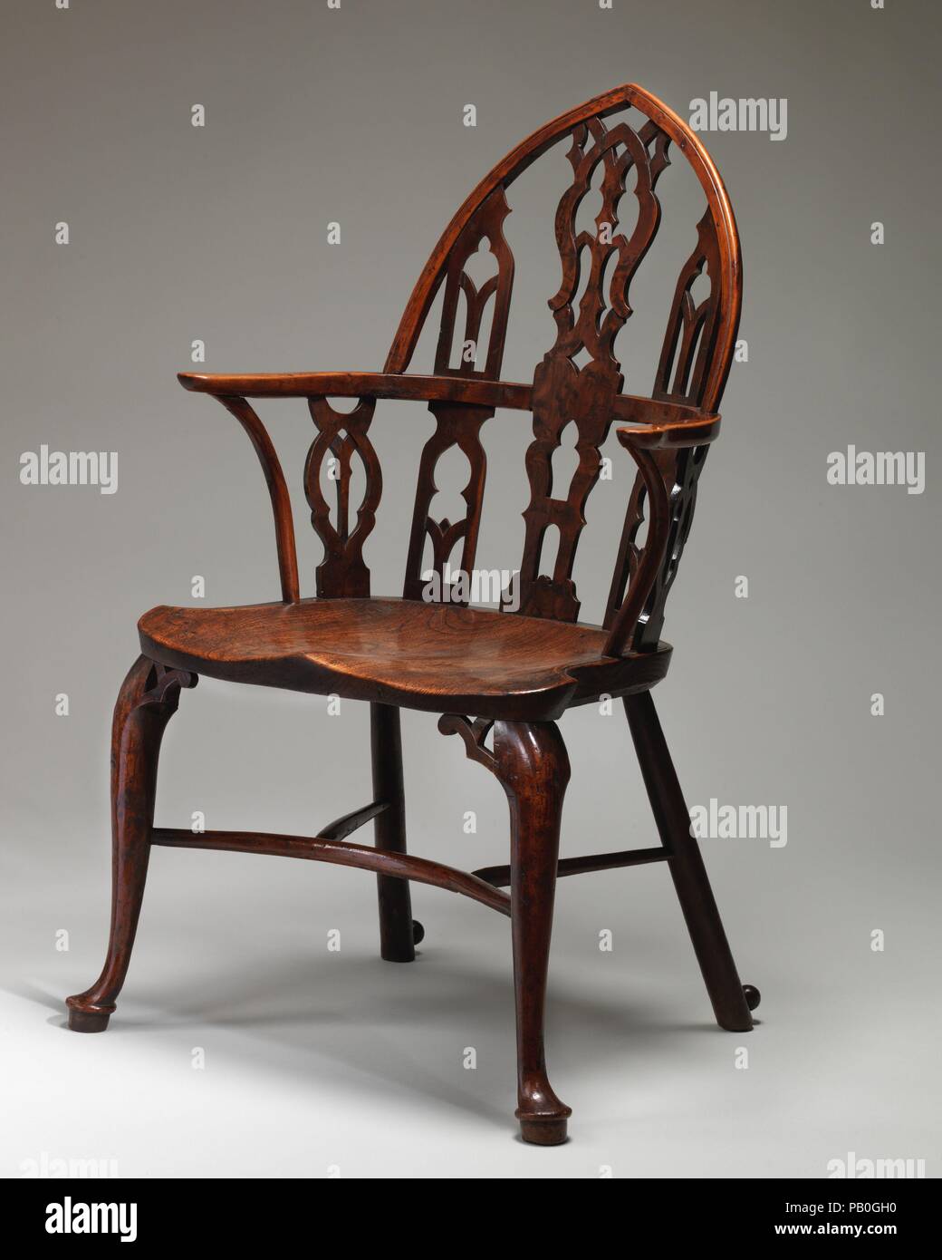 Gothic Windsor armchair (one of a pair). Culture: British, Thames Valley. Dimensions: Overall (confirmed): 41 3/4 × 23 × 22 in. (106 × 58.4 × 55.9 cm);  Height of seat: 18 1/4 in. (46.4 cm);  Width of seat: 22 in. (55.9 cm). Date: ca. 1760s.  Quintessentially English country furniture, this pair of Windsor armchairs (see also 2016.250) is a variant of the more traditional bow-back design. With its pointed arch-shaped back and openwork splats displaying Gothic tracery, these chairs beautifully reflect the Gothic taste which became fashionable in England in the middle of the 18th century. Museum Stock Photo